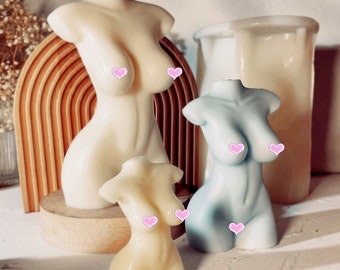 May include: Three decorative torso-shaped candles in different sizes. The largest candle is white, the middle candle is light blue, and the smallest candle is cream colored.