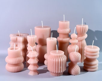 May include: A collection of ten pink, decorative candles with various shapes and textures. The candles are arranged on a light gray surface.