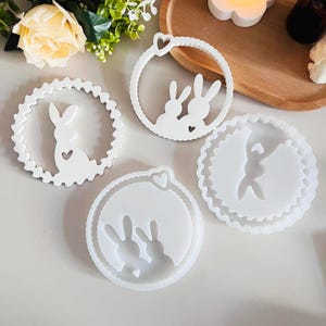 Könnte beinhalten: Vier weiße Silikonformen in Form von Hasen mit Herzen. Die Formen sind zum Herstellen von Kunsthandwerk aus Harz.