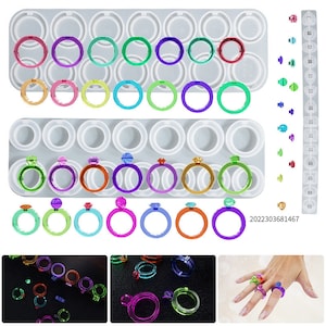 May include: Image of resin ring moulds in a variety of colours, including green, purple, orange, and blue. The image also shows finished resin rings with gemstone accents and a hand wearing several rings.