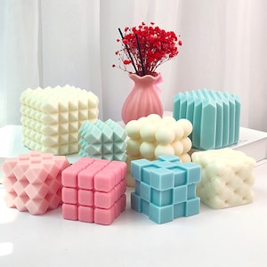 Könnte beinhalten: Sortiment an bunten geometrischen Kerzen, darunter ein rosa Würfel, ein blauer Würfel, eine weiße Kugel, ein rosa Diamant, ein blauer Diamant, ein weißer Diamant und ein weißes gestepptes Design.