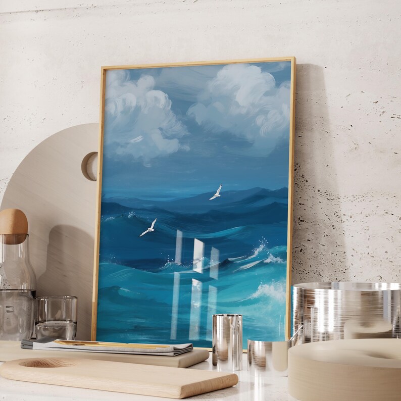 Puede incluir: Una pintura enmarcada de un paisaje mar&iacute;timo con nubes blancas y agua azul. La pintura presenta dos p&aacute;jaros blancos volando sobre el agua.