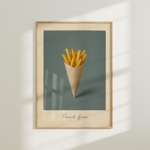 May include: A framed print showing a cone of golden chips against a teal background. The chips are in a brown paper cone. The words "French fries" are written in cursive at the bottom of the print.