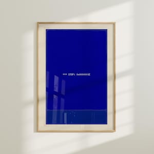 May include: Framed art print featuring a solid blue background with the text "*** STOP: 0x0000001E" in white. The artwork is encased in a light wood frame, creating a minimalist aesthetic. The print is displayed against a white wall.