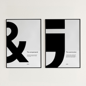 Può includere: Due poster incorniciati neri con sfondi bianchi. Il poster a sinistra presenta un grande simbolo ampersand nero con il testo "The ampersand" sotto. Il poster a destra presenta un grande simbolo punto e virgola nero con il testo "The semicolon" sotto.