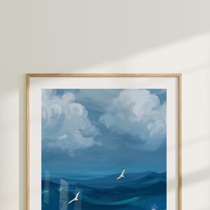 Puede incluir: Una pintura enmarcada de un paisaje mar&iacute;timo con dos gaviotas blancas volando sobre un oc&eacute;ano azul con nubes blancas en el cielo.