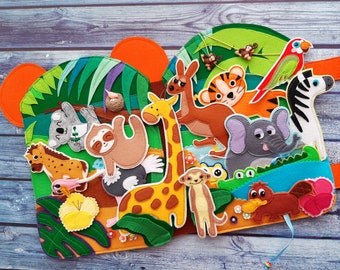 May include: A felt play mat with various animal characters, including a giraffe, kangaroo, elephant, zebra, and a platypus. The mat is green and brown with a variety of textures.