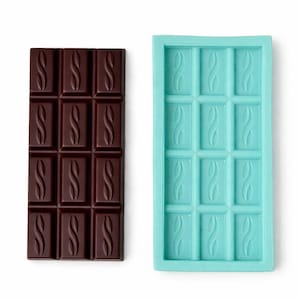 May include: A dark chocolate bar with a decorative design next to a turquoise silicone mold. The chocolate bar is rectangular with a pattern of stylized letter "S" shapes in each of the 12 squares. The mold has the same design.