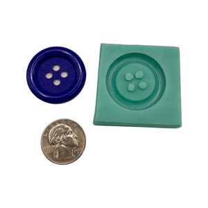 Könnte beinhalten: Ein blauer Knopf mit vier Löchern, eine türkisfarbene Knopfform und eine Münze werden auf weißem Hintergrund gezeigt. Der Knopf ist rund und hat ein glänzendes Finish. Die Knopfform ist quadratisch und hat einen Knopf-Form-Eindruck.