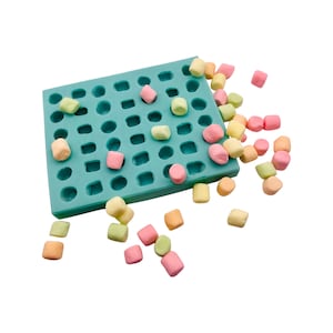 May include: A teal silicone mould with various shaped cavities, partially filled with pastel-coloured marshmallows. Scattered marshmallows of pink, yellow, orange, and green surround the mould, suggesting a confectionery theme.