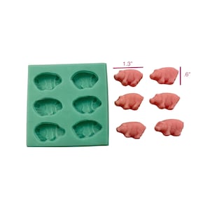 May include: A teal silicone mold with six pig-shaped cavities, alongside six pink pig-shaped candies. The candies measure approximately 1.3 inches long and 0.6 inches high. Ideal for crafting or baking, the mold creates detailed pig shapes.