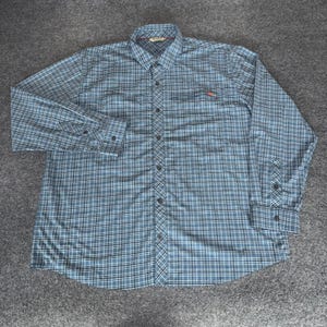 May include: A long-sleeved, button-down shirt in a blue and white plaid pattern. The shirt has a collared neckline, a chest pocket, and buttoned cuffs. A small red logo is visible on the chest pocket.
