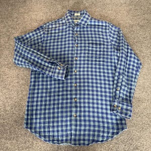 May include: Blue and green plaid button-down shirt. The long-sleeved shirt features a classic collar, a chest pocket, and buttoned cuffs. The shirt is made of a soft, woven fabric and has a relaxed fit.