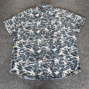 May include: Short-sleeved button-down shirt with a tropical leaf pattern in shades of blue and white. The shirt has a classic collar and button closure. The fabric appears to be a lightweight cotton or linen blend.