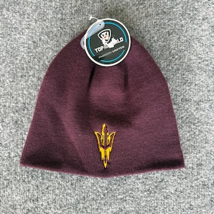 May include: A maroon knit beanie featuring a yellow embroidered trident logo on the front. A circular product tag is attached to the top, displaying the text Top of the World and Passion Unites with a shield graphic and a small logo icon.