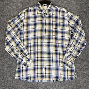 May include: A long-sleeved button-down shirt with a plaid pattern in white, navy blue, and olive green. The shirt has a classic collar and buttoned cuffs. The fabric appears to be lightweight, suitable for warmer weather.