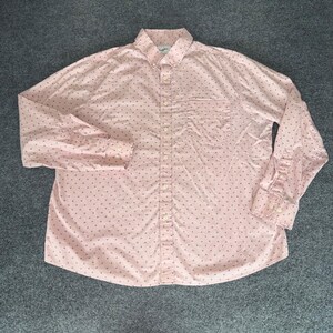 May include: A light pink long-sleeve button-down shirt featuring a repeating pattern of small dark blue geometric shapes. The shirt includes a pointed collar, a single chest pocket on the left side, and matching buttons along the front placket.