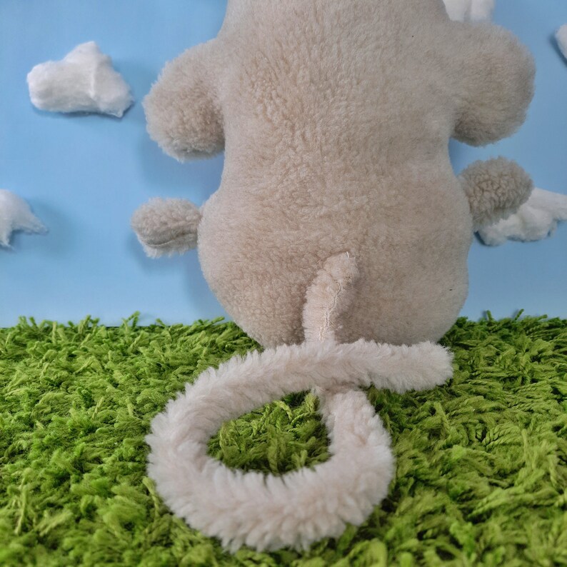 May include: A plush toy in the shape of a gray monkey with a long, fluffy tail. The monkey is sitting on a green, grassy surface.