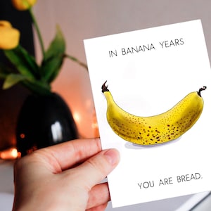 May include: A white card with the text "In banana years, you are bread." and a drawing of a yellow banana with brown spots.