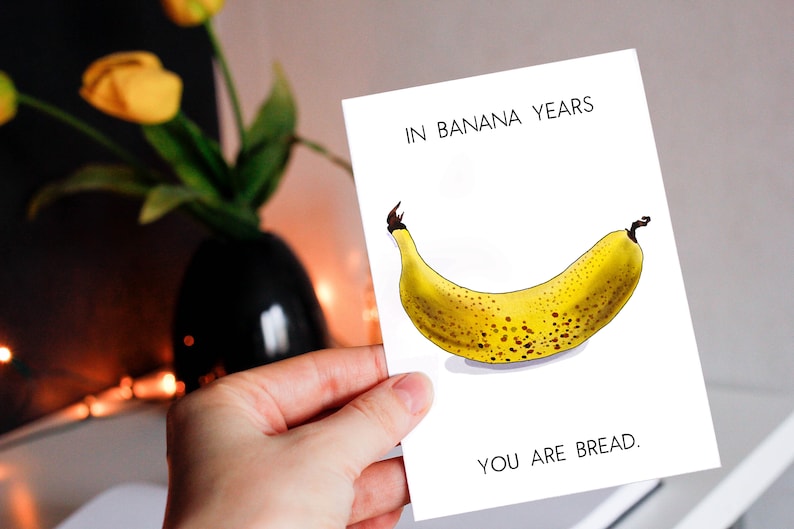 May include: A white card with the text "In banana years, you are bread." and a drawing of a yellow banana with brown spots.