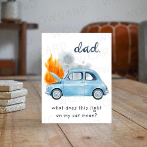 May include: A greeting card with a watercolor illustration of a light blue car on fire. The text reads "dad," and "what does this light on my car mean?" The card is on a wooden surface.
