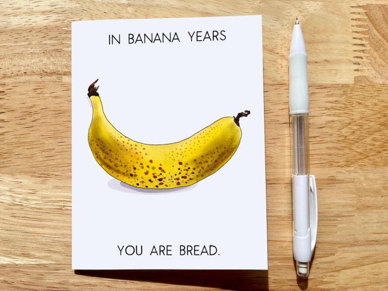 May include: A greeting card with a yellow banana with brown spots and the text "IN BANANA YEARS YOU ARE BREAD."