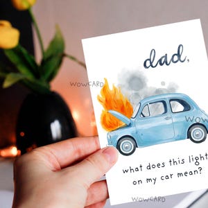 May include: A greeting card with a watercolor illustration of a light blue car on fire. The card reads "dad, what does this light on my car mean?" in a playful font. The card is held in a hand.
