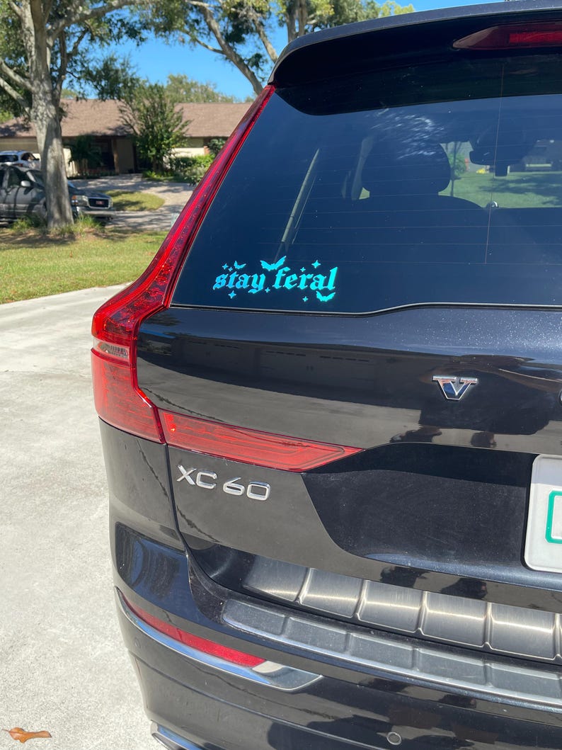 May include: A black Volvo XC60 with a teal blue "stay feral" sticker on the back window.