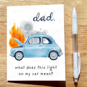 May include: A greeting card with a watercolor illustration of a light blue car on fire, with the text "dad," and "what does this light on my car mean?" A white pen is to the right of the card.