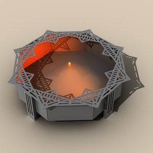 May include: A gray geometric candle holder with an intricate star-like design around the rim. The interior glows with an orange light, and a small candle is lit in the center. The candle holder casts a shadow on the surface.