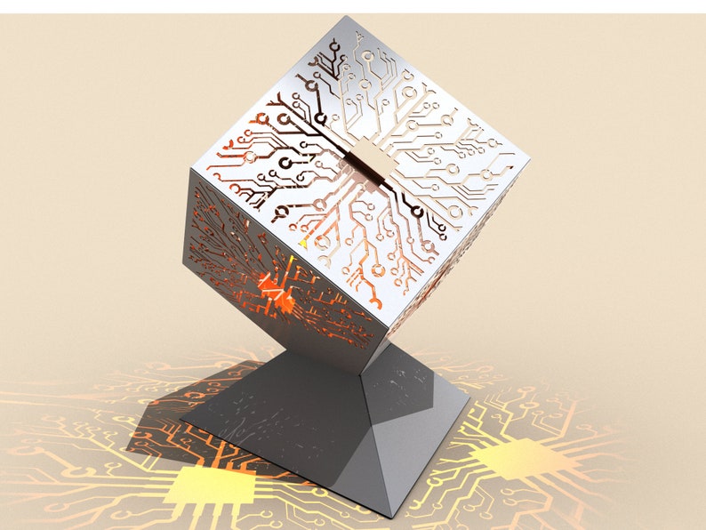May include: A silver cube with a circuit board design cut out, illuminated from within. The cube is on a silver stand with a circuit board design on the base.