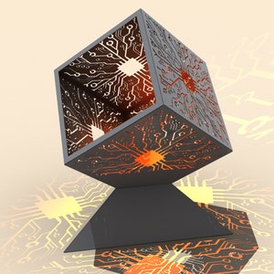 May include: A black metal cube with a circuit board design, lit from within with orange and yellow lights. The cube is sitting on a black triangular base.