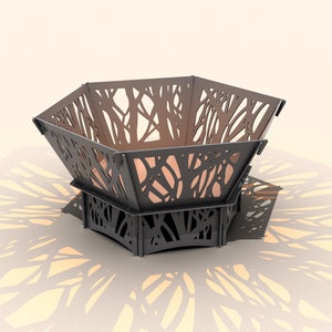 May include: A black metal fire pit with a hexagonal shape and a decorative cut-out design resembling branches. The fire pit is sitting on a white surface.