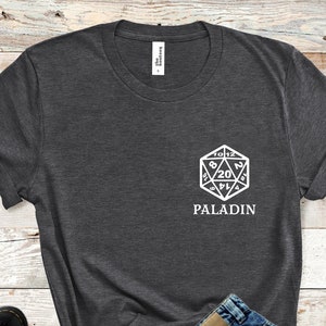 May include: Dark gray t-shirt with a white graphic of a twenty-sided die and the word "PALADIN".