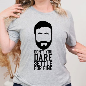 May include: A gray t-shirt with a black and white illustration of a man's face and the text "Don't you dare settle for fine."