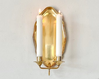 Antique Scandinavian brass wall candle sconce with a curved frame and two candle holders.