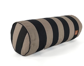 May include: A cylindrical bolster pillow with alternating black and tan vertical stripes. The pillow has rounded ends and a zipper closure. The fabric appears to be a textured linen or similar material. A small, square tag is sewn on the side.