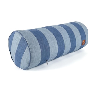 May include: A cylindrical bolster pillow with alternating blue and light blue stripes. The pillow has rounded ends and a zipper closure. The fabric appears to be linen or a similar textured material. A small tag is visible on the side.