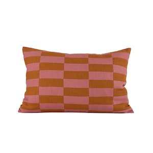 May include: Rectangular decorative pillow with a checkerboard pattern. The pillow features alternating horizontal stripes of dusty rose and burnt orange. The pillow is made of a textured fabric and is designed for home decor.
