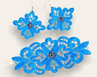 May include: A set of blue lace jewelry featuring a bracelet and earrings. The jewelry is decorated with small, dark blue rhinestones.