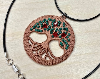 May include: A copper-colored tree of life pendant with green and red beads, hanging from a black cord necklace with a silver clasp.