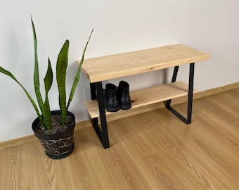 Könnte beinhalten: Eine Holzbank mit schwarzem Metallgestell und einem Regal. Die Bank hat eine natürliche Holzoptik und steht auf einem hellen Holzboden. Im Vordergrund steht eine Topfpflanze.