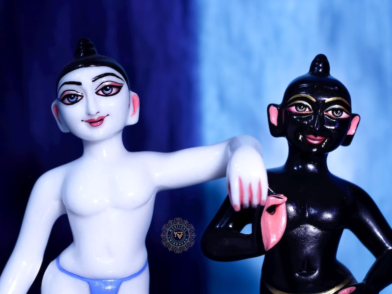May include: Two statues of figures with stylized features. One is white with a blue thong, the other is black. Both have black hair, pink lips, and detailed facial features. The background is a gradient of blue.