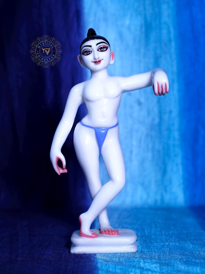 May include: A white figurine of a young person with a blue thong, standing on a white base. The figurine has black hair, painted facial features, and red accents on the hands and feet. The background is a gradient of blue.