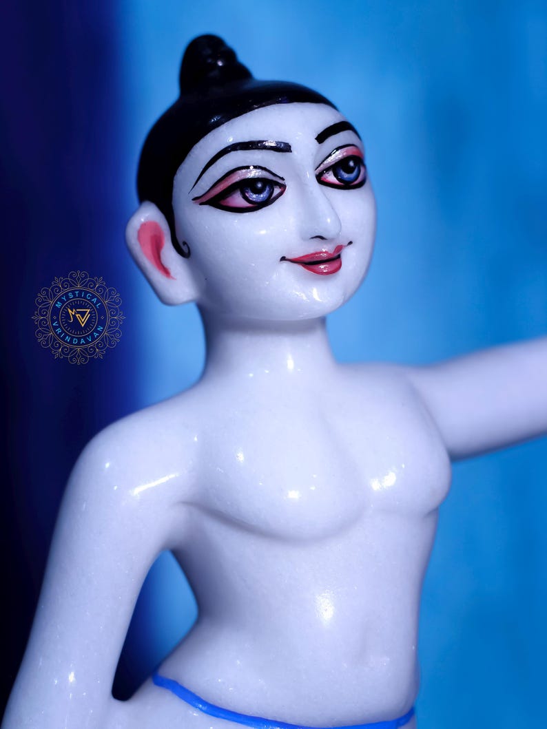 May include: A white marble statue of a person with black hair and painted facial features, including pink lips and blue eyes. The figure is wearing a blue garment around the waist and has one arm extended. The background is a gradient of blue.