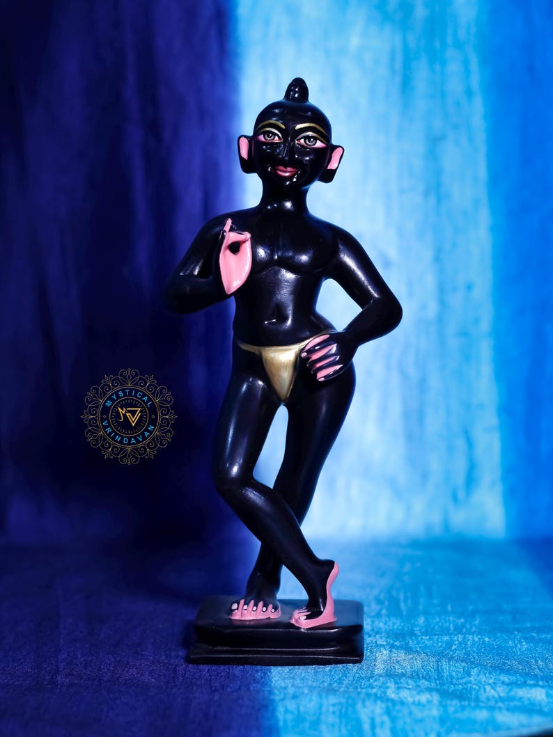 May include: A black figurine of a person with pink accents on the ears, hands, and feet, and a gold-colored loincloth. The figurine is standing on a black base. The background is a gradient of blue.