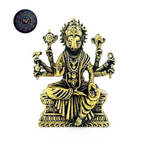 May include: A gold-colored metal statue of a deity with multiple arms holding various objects. The deity is seated on a throne with intricate details. The statue has a black and gold color scheme.