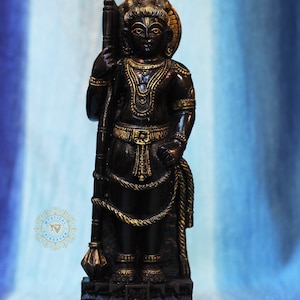 May include: Black statue of a Hindu deity holding a staff, with gold accents and a decorative base.