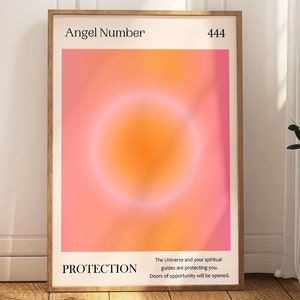 May include: A framed print with a pink and orange gradient background and a white circle in the center. The text "Angel Number 444" is at the top of the print and the text "Protection" is at the bottom. The text "The universe and your spiritual guides are protecting you. Doors of opportunity will be opened." is below the text "Protection".