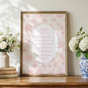 May include: A framed wall art print featuring a pink floral background with a central white oval containing the text: Trust in the Lord with all your heart and lean not on your own understanding; in all your ways submit to Him, and He will make your paths straight. Proverbs 3:5-6.